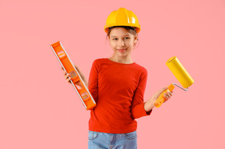 Little architect with level and paint roller on pink backgroundの写真素材
