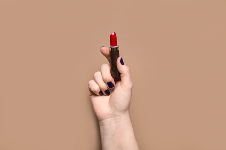 Female hand with red lipstick on brown backgroundの写真素材