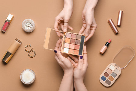Female hands with different decorative cosmetics and earrings on brown backgroundの写真素材