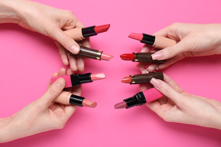 Female hands with many lipsticks on pink backgroundの写真素材