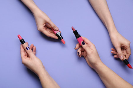 Female hands with lipsticks on purple backgroundの写真素材
