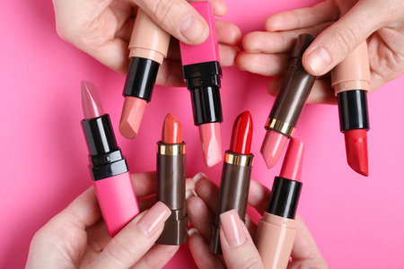 Female hands with many lipsticks on pink backgroundの写真素材
