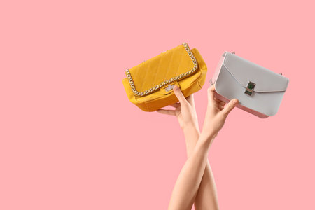 Female hands with different stylish women's bags on pink backgroundの写真素材