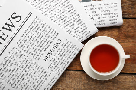 Newspapers with cup of tea on wooden backgroundの写真素材