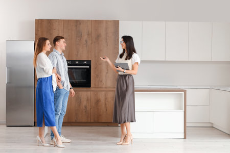 Female real estate agent showing couple kitchen in new houseの写真素材