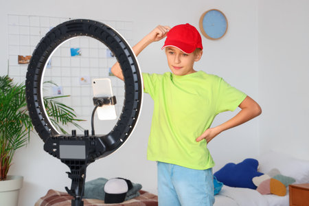 Teenage blogger with cap recording video at homeの写真素材