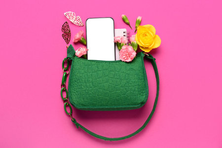 Composition with stylish female handbag, modern mobile phone and flowers on pink backgroundの写真素材