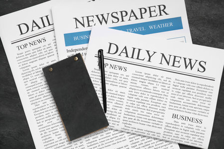Newspapers with notebook and pen on black grunge backgroundの写真素材