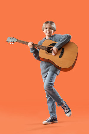 Little boy playing guitar on orange backgroundの写真素材