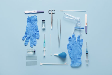 Medical gloves with gynecological speculum, pap smear test tools and syringes on blue backgroundの写真素材