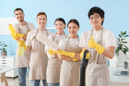Group of young janitors with cleaning supplies in officeの写真素材