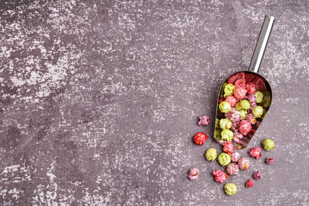 Metal scoop with sweet colorful popcorn on dark tableの写真素材