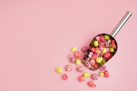 Metal scoop with sweet colorful popcorn on pink backgroundの写真素材