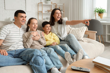 Family watching TV on sofa at homeの写真素材
