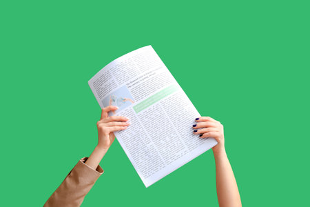 Female hands with newspaper on green backgroundの写真素材