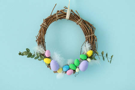 Beautiful Easter wreath decorated with eggs and branches on blue wall