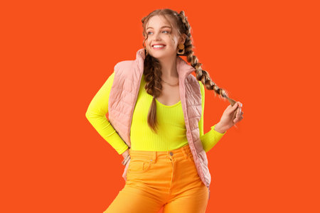 Happy smiling young woman with braids on orange background