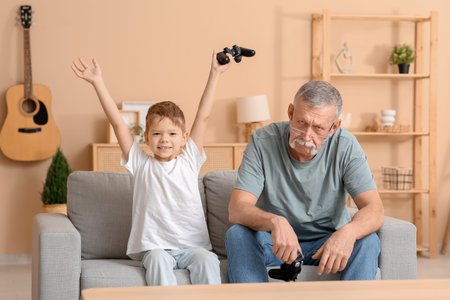 Grandfather with his cute little grandson playing video games at home