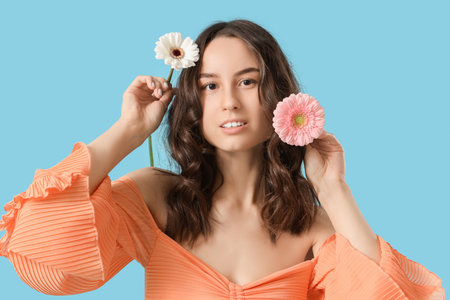 Beautiful young woman with spring flowers on blue background, closeupの写真素材