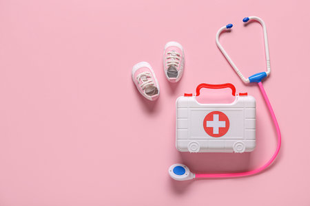 Toy first aid kit with kid's shoes and stethoscope on pink background. Top viewの写真素材