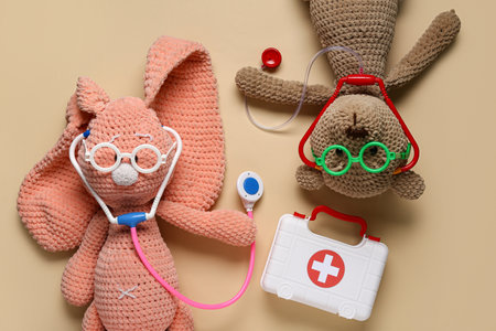 Toy first aid kit with teddy bear, toy bunny and stethoscope on beige background. Top viewの写真素材