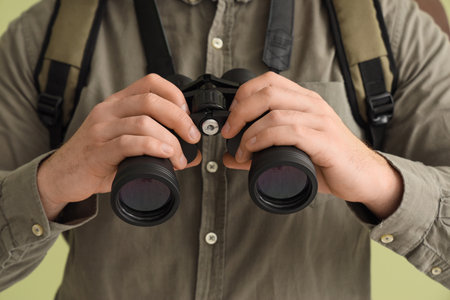Male tourist with binoculars on green background, closeupの写真素材