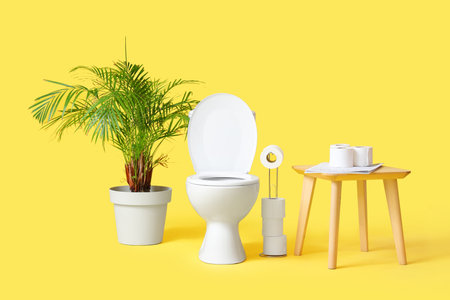 Toilet bowl with paper rolls, table and palm tree on yellow backgroundの写真素材