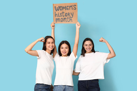 Beautiful women holding cardboard with text WOMEN'S HISTORY MONTH on blue backgroundの写真素材