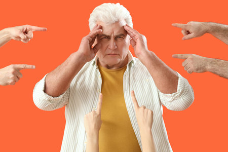 People pointing at stressed mature man on orange background. Accusation concept
