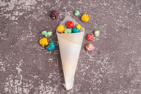 Paper cone with sweet colorful popcorn on dark backgroundの写真素材