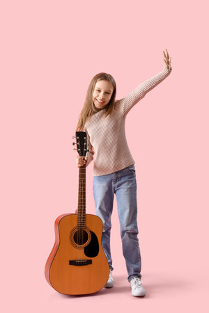 Teenage girl with acoustic guitar on pink backgroundの写真素材