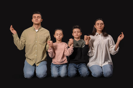 Family praying together on dark backgroundの写真素材