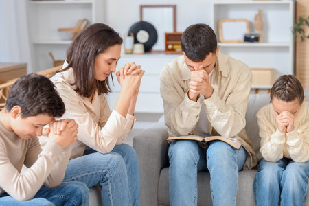 Family with Holy Bible praying on sofa at homeの写真素材