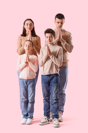 Family praying together on pink backgroundの写真素材