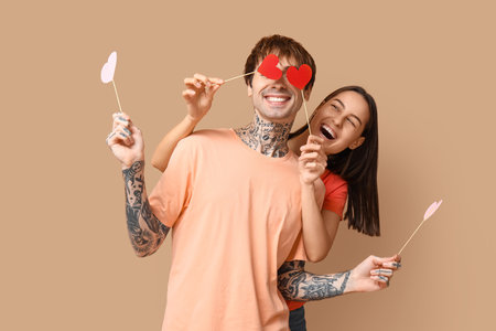 Funny young couple with paper hearts on beige backgroundの写真素材