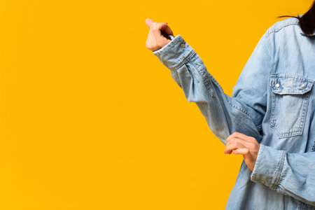 Beautiful young Asian woman in stylish denim jacket on yellow background, closeupの写真素材