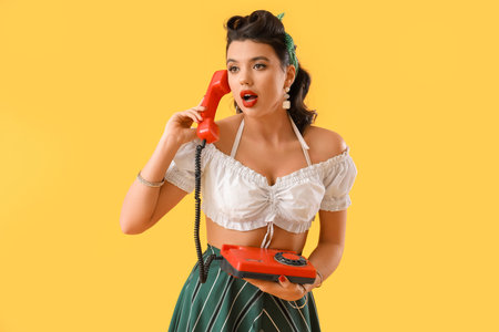 Attractive pin-up woman talking by telephone on yellow backgroundの写真素材