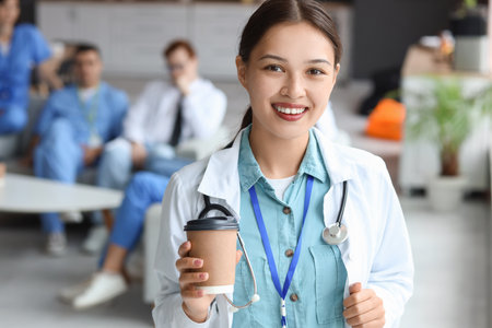 Female Asian doctor with coffee cup in hospital rest roomの写真素材