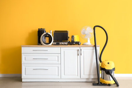 Different household appliances on kitchen counter near yellow wallの写真素材