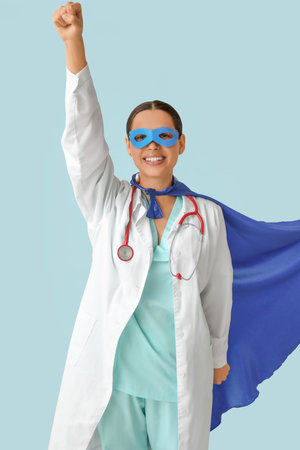 Beautiful female doctor dressed as super hero on blue backgroundの写真素材