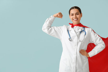 Beautiful female doctor in superhero costume showing muscles on blue backgroundの写真素材