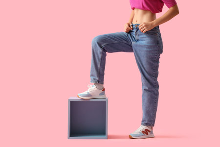 Young woman in stylish jeans pants on pink background