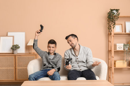 Father and his little son playing video games on sofa at homeの写真素材