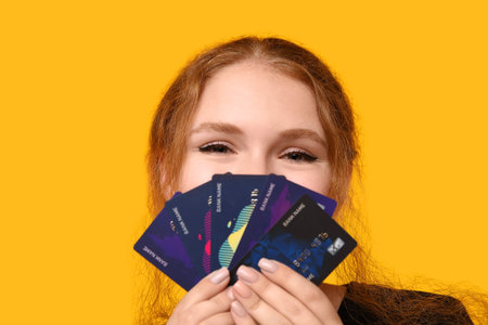 Beautiful young woman with credit cards on yellow background