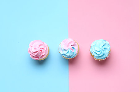 Delicious cupcakes with blue and pink frosting on color background. Gender reveal party conceptの写真素材