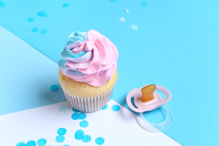 Delicious cupcake with confetti and pacifier on blue background. Gender reveal party conceptの写真素材