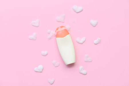 Bottle of cosmetic product with heart shaped foam on pink backgroundの写真素材