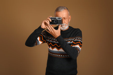 Senior man with photo camera on brown backgroundの写真素材