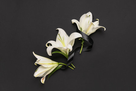Beautiful lily flowers with black funeral ribbon on dark backgroundの写真素材