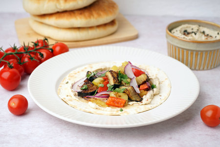 Plate of tasty pita bread with grilled vegetables on white background